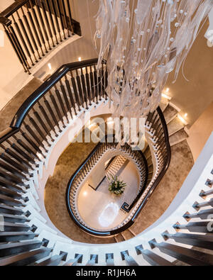 Vista al di sopra di una scalinata a spirale con luce pendente Foto Stock