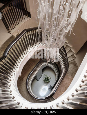 Vista al di sopra di una scalinata a spirale con luce pendente Foto Stock