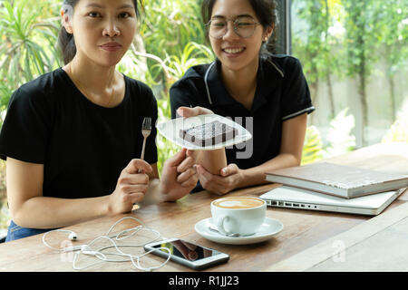 Amici di sesso femminile avente pausa caffè con torta brownie in coffee shop. Foto Stock