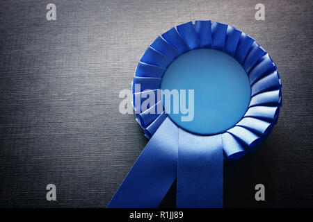 Premio blu rosette con nastri e copia spazio su sfondo nero Foto Stock