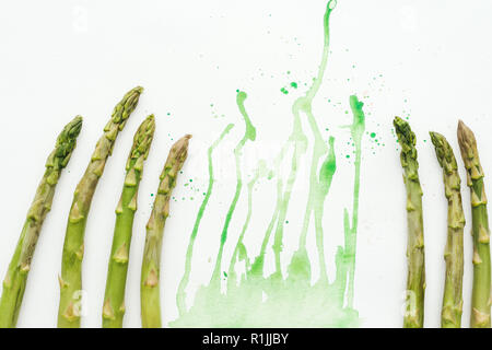 Vista dall'alto di asparagi freschi steli sulla superficie bianca con verde acquerello blot Foto Stock