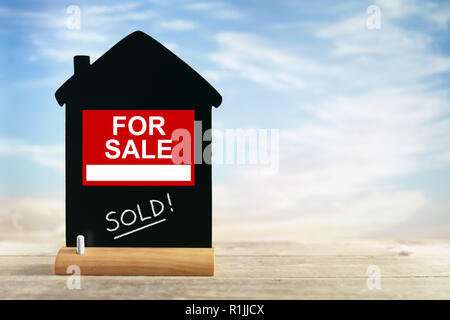 Agente immobiliare in vendita segno con venduti sulla forma della casa chalk blackboard Foto Stock