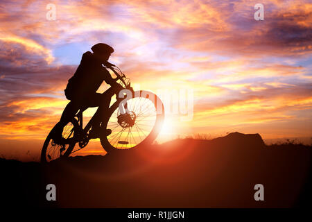 Mountain Biker silhouette contro il concetto di tramonto per conseguimento, conquistando le avversità e di esercizio Foto Stock