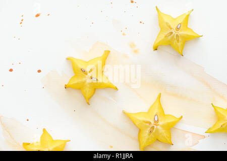 Vista superiore della stella gialla frutti sulla superficie bianca con acquerello giallo Foto Stock