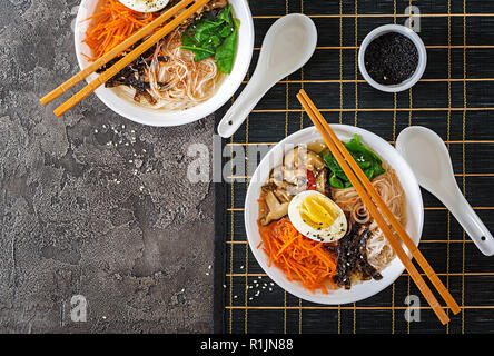 La dieta vegetariana ciotola di zuppa di spaghetti di funghi shiitake, carota e uova sode. Il cibo giapponese. Vista dall'alto. Lay piatto Foto Stock