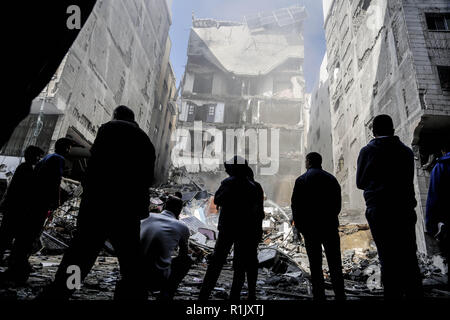 La città di Gaza, di Gaza, di Gaza. Xiii Nov, 2018. I palestinesi sono visto in piedi accanto ai resti di un edificio che è stata completamente distrutta da un attacco aereo israeliano nella striscia di Gaza City. Credito: Mohamed Zarandah SOPA/images/ZUMA filo/Alamy Live News Foto Stock