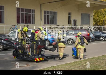 Stati Uniti Esercito vigili del fuoco civili dalla U.S. Army Garrison (USAG) Ansbach dimostrare evacuazione e salvataggio procedure al battaglione e quartier generale di brigata a Storck Baracks in Illesheim, Germania, 10 ottobre, 2018. La dimostrazione è parte del presidio di ricorrenza annuale per la prevenzione degli incendi e per la settimana. Foto Stock