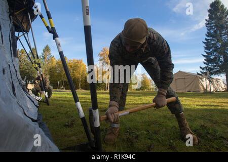 Stati Uniti Marine Corps Lance Cpl. Romero Boyd con sede reggimento, 2° Marine Logistics Group in avanti, utilizza una mazza per fissare un rifugio durante la costruzione della seconda MLG in avanti il comando del centro di funzionamento per Trident frangente 18 in Norvegia, il 7 ottobre 2018. Trident frangente 18 è parte di un esercizio pianificato serie per migliorare gli Stati Uniti e gli alleati della NATO la loro capacità di lavorare insieme collettivamente a condurre operazioni militari sotto condizioni impegnative. Foto Stock