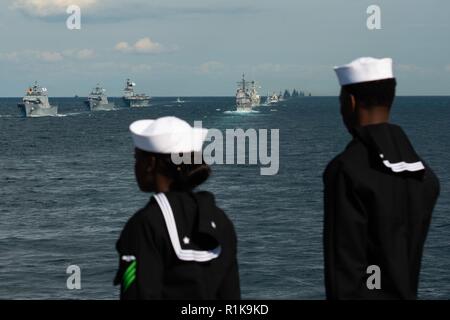 Acque al largo della penisola coreana (ott. 11, 2018) i marinai a bordo del distribuita portaerei USS Ronald Reagan (CVN 76) uomo le rotaie come navi multinazionale del vapore in formazione durante un esercizio presso la Repubblica di Corea (ROK) flotta internazionale di revisione (IFR) 2018. IFR 2018 è ospitato dalla Repubblica di Corea Navy per aiutare a migliorare la reciproca fiducia e confidenza con le marine di tutto il mondo. Ronald Reagan è distribuita negli Stati Uniti 7 flotta area di operazioni a sostegno della sicurezza e della stabilità nella regione Indo-Pacifico. Foto Stock