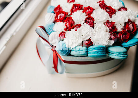 Composizione festosa di rosoni decorativi e amaretti in una scatola a forma di cuore Foto Stock