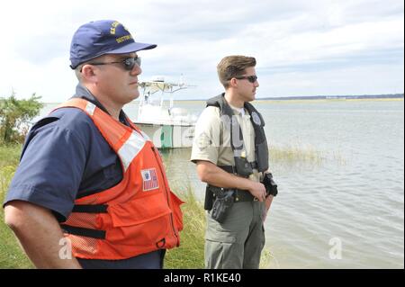 Coast Guard Petty Officer 1. Classe Brian O'Neil, una scienza marina tecnico assegnato alla chiave settore ovest, e Brandon Bonner, un funzionario della fauna selvatica con la Carolina del Nord delle risorse della fauna selvatica Commissione, stand a terra con il compito di supervisionare il processo di rimozione dei materiali pericolosi da una nave nelle vicinanze che era stato spostato su di un eco-area sensibile, Atlantic Beach, N.C., domenica, il 14 ottobre 2018. Il supporto di emergenza funzione-10 comando unificato, composta di Stati Uniti Guardia costiera e la Carolina del Nord la fauna selvatica delle risorse, la Commissione ha collaborato con le agenzie di assistenza come il National Oceanic e Foto Stock