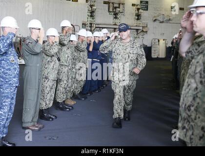 NEWPORT NEWS, Va. (ott. 11, 2018) Lt. La Cmdr. Edward chinoni, da San Juan, Puerto Rico, restituisce il saluto di USS Gerald Ford (CVN 78) Membri di equipaggio come egli è rediretto a terra. Ford è attualmente in fase di post-shakedown periodo di disponibilità a Huntington Ingalls Industries-Newport News la costruzione navale. Foto Stock