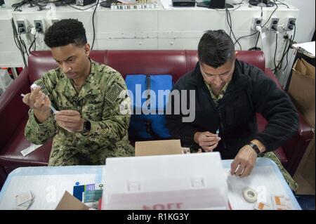 SAN DIEGO (ott. 16, 2018) Ospedale Corpsman 2a classe Nathaniel Garrett, sinistra, da St. Louis, e Hospitalman Emmanuel Flores, da Chicago, preparare le siringhe durante il virus influenzale vaccinazioni a bordo dell'assalto anfibio nave USS Bonhomme Richard (LHD 6). Bonhomme Richard è nel suo homeport di San Diego. Foto Stock