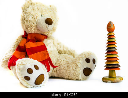 Fluffy orsacchiotto di peluche con sciarpa rossa e anello di legno raccoglitore su sfondo bianco. Vecchi giocattoli d'epoca. Foto Stock