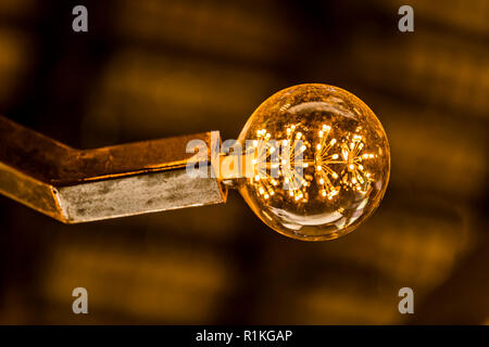 Decorative lampada a LED in acciaio lampada titolare in arancione atmosferica golden ombra contro morbido sfondo sfocato Foto Stock