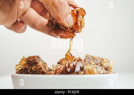 Pezzi di favi in una ciotola. Fresh ape miele in favo pezzi su sfondo bianco. Foto Stock