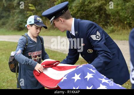 Stati Uniti Air Force Sergeant del personale Justin Spencer, uno specialista dei servizi assegnati al centottantesimo Fighter Wing, Ohio Air National Guard, insegna Isaia Cladden, un boy scout di truppa 485 fuori di Bowling Green, Ohio, come piegare un flag durante il Camp Frontier cinquantesimo anniversario camporall 6 ott. 2018 in Pioneer, Ohio. Avieri dal centottantesimo Fighter Wing, Ohio Air National Guard si sforzano di dare di più per la comunità che essi ricevono. Foto Stock