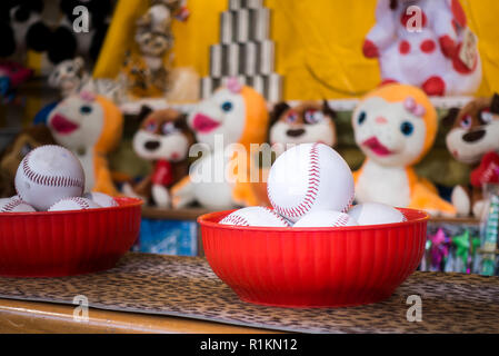 Close-up di palle da baseball per il gioco di buttare a vasetti in una fiera. Sullo sfondo i vasi ed il premio marionette Foto Stock