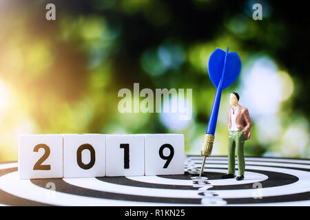 Imprenditore guardando avanti nel 2019 per il lavoro di progettazione con obiettivi e target il concetto di business, dart blu sulla scheda e la sfocatura dello sfondo verde Foto Stock