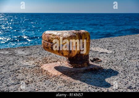 Vecchio arrugginito bollard su un molo sul mare in Grecia Foto Stock