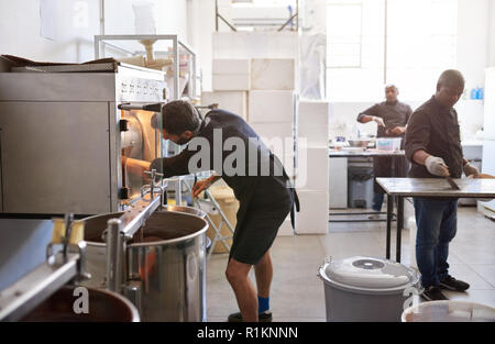 Lavoratore in una fabbrica di cioccolato tostatura di semi di cacao Foto Stock