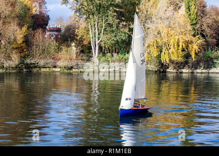 Un uomo in una piccola barca a vela sul Fiume Tamigi al prosciutto, LONDRA, REGNO UNITO, Orleans giardini e una galleria di immagini in background Foto Stock