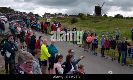 Sostenitori pronti a fare il tifo per i piloti, 2017 Tour della Gran Bretagna cycle race, con mulino a vento a Brill, Buckinghamshire, Inghilterra Foto Stock