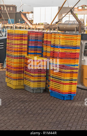 Vari colori di plastica vuote casse di pesce ammucchiate sul quay Foto Stock