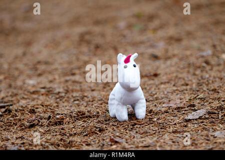 Bambina bambino giocattolo morbido unicorn perso in un parco giochi per i bambini Foto Stock