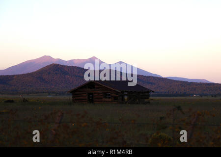 Vecchia casa in Arizona contro lo sfondo delle montagne durante il tramonto Foto Stock