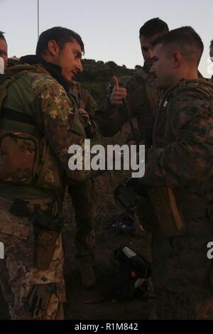 Sardegna, Italia (ott. 12, 2018) DEGLI STATI UNITI Marine Capt. Robert Atkinson, a destra il comandante di plotone per la forza della ricognizione Det. del Battaglione Team di atterraggio 3/1, 13 Marine Expeditionary Unit (MEU), parla di Navale Italiana fante, Alex Semararo, dopo una nave-shore assalto anfibio durante la fase di esercizio la Mare Aperto, Ottobre 12, 2018. La Mare Aperto è progettato per migliorare la combinata di capacità di combattimento, aumentare la capacità operativa e di rafforzare le relazioni tra i partecipanti di esercizio. Foto Stock