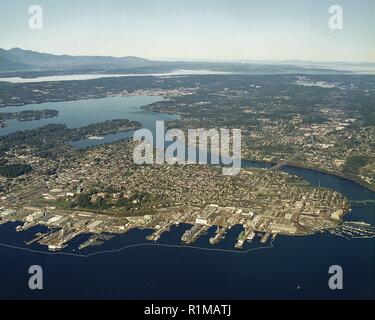 Puget Sound Naval Shipyard e il centro cittadino di Bremerton territoriale waterfront come visto da oltre Port Orchard guardando ad ovest. Le vie navigabili Sinclair ingresso, Port Washington si restringe e ingresso di coloranti sono visibili nella foto. Montagne Olimpiche sono in background. Foto Stock