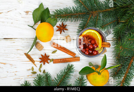 Natale rimuginassero vino rosso con cannella, cardamomo e anice stellato, arance, mandarini e mirtilli rossi su un vecchio tavolo luminoso. Tradizionale bevanda calda per Foto Stock