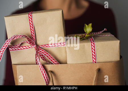 Primo piano di una giovane donna caucasica tenendo una carta shopping bag pieno di doni contro un sfondo bianco Foto Stock