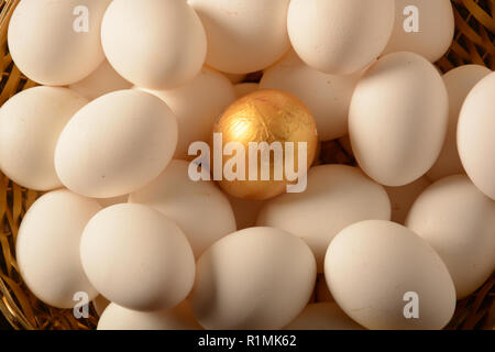 Golden Egg in mezzo le uova bianche, immagine simbolica per essere diversi, in piedi fuori dalla folla Golden Egg in mezzo le uova bianche, immagine simbolica per essere Foto Stock