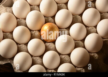 Golden Egg in mezzo le uova bianche, immagine simbolica per essere diversi, in piedi fuori dalla folla Golden Egg Foto Stock
