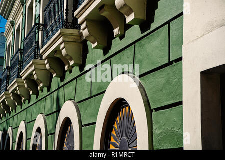 Parete di facciata sul verde sfondo intonacato in San Juan, Porto Rico. Casa con finestre e balconi decorativi. La simmetria e la geometria di urban concept. Costruzione e ristrutturazione. Foto Stock