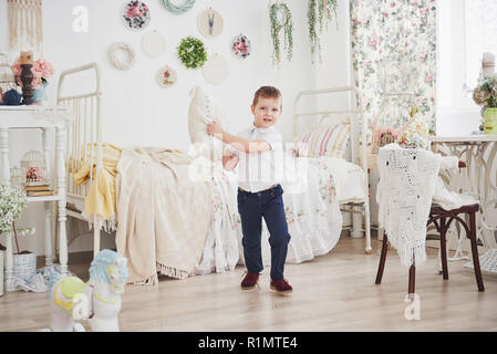 Little Boy in camicia bianca con cuscino. Pillow Fight Foto Stock