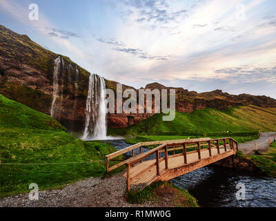 Cascata Seljalandfoss al tramonto. Ponte sul fiume. Natura fantastica. L'Islanda Foto Stock