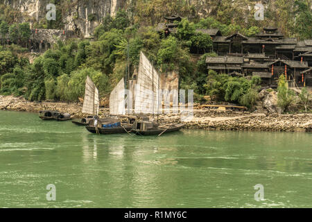 Sampans con vele lungo il fiume Yangtze con case tradizionali in background Foto Stock