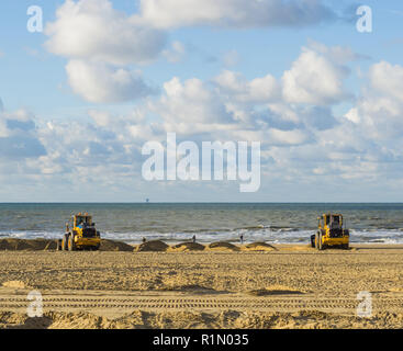 Promotori di terra che lavorano nel loro macchine presso la spiaggia per manutenzione spostando la sabbia Foto Stock