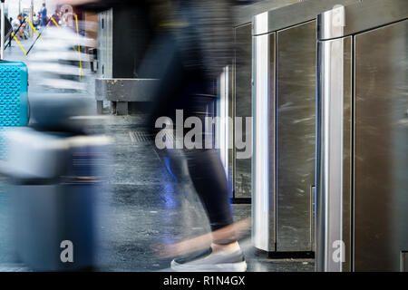 Vista laterale di una donna con una valigia scorrevole passando per acciaio inox cancelli di ticket in un trasporto pubblico dalla stazione di Parigi con motion blur Foto Stock