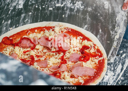 Pizza con pancetta affumicata su una paletta di legno Foto Stock