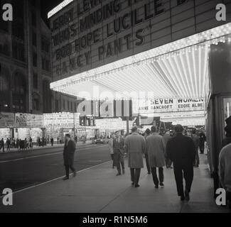 1963, serata in Times Square e Midtown Mahattan, il quartiere dei teatri di New York e le luci al neon di cinema e teatri illumina la strada. Mostra in questo momento, il Jerry Lee Lewis commedia film, 'chi occupa il negozio' e il film "fancy pants", interpretato da Bob Hope e Luciille palla. Foto Stock