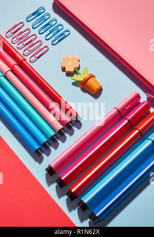Fiore decorativo tra gli articoli di cancelleria su uno sfondo blu Foto Stock