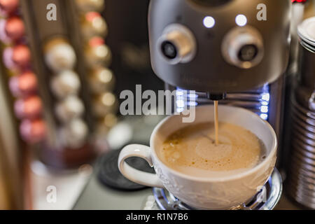 Caffè Espresso capsule e macchina maker su una tavola di legno, blur cialde di caffè e fagioli sfondo Foto Stock