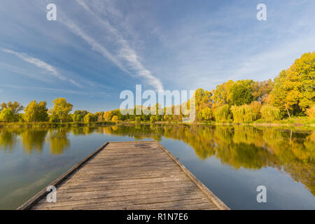 Laguna specchio arrotondati da montagne, autunno magnifico lago di riflessione e colorati di foglie di albero Foto Stock