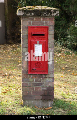 Un mattone montato Royal Mail cassetta di raccolta a Sawbridgeworth, Hertfordshire dal regno della regina Elisabetta II, ER, coperte di muschio e sul verde Foto Stock