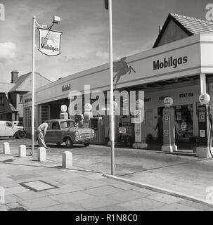 Degli anni Cinquanta, storico i giorni d'oro dell'automobilismo, una stazione di servizio sttendant colloqui per un conducente di un auto presso le pompe di benzina al Mobilgas Ravenscroft stazione di servizio sulla Great West Road, Londra, Inghilterra, Regno Unito. Foto Stock