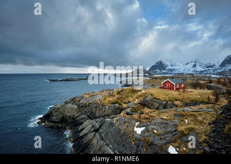 Clif con tradizionale rosso rorbu casa sulle Isole Lofoten in Norvegia Foto Stock